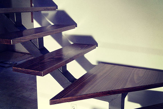 Escalera realizada en piezas maciza de pino valsaín, con una terminación de barniz de poliuretano de alta resistencia y teñido en roble rústico. Es una estructura de diseño voladizo que le da una sensación de ligereza y crea un espacio visual abierto para dar una apariencia a la estancia más abierta y amplia. Su apariencia no tiene nada que ver con su solidez, ya que es un sistema bastante sólido y consistente. 