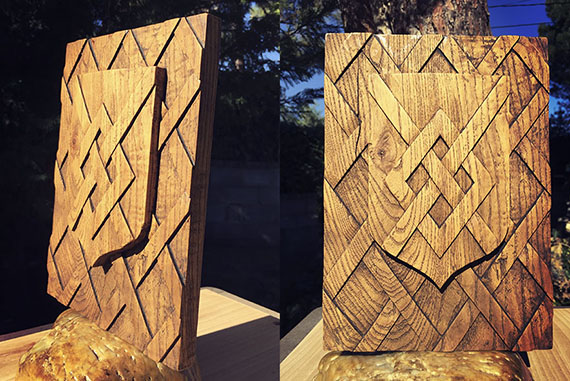 Reproducción en madera de arce de un escudo de armas con diseños geométricos sencillos, con un acabado de teñido y encerado.