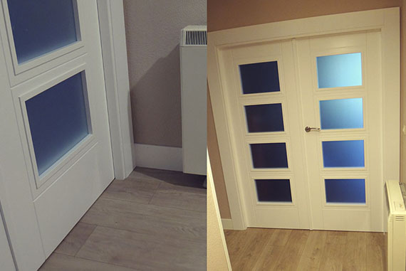 En esta fotografía se puede ver una obra de carpintería completa. Los marcos fueron conservados y el resto de la carpintería se adapto a estos, puesto que estos tenían una medida especial que quiso ser conservada. En la fotografía se puede ver el detalle de la precisión en las terminaciones del suelo, zócalo y puerta encajando al de forma precisa con el marco. El resultado final es un aspecto totalmente nuevo diferente al inicial con tan solo unos pocos cambios en la casa. El acabado en laca blanca fue recomendado por la escasez de luz que presenta esta casa. El suelo es de tarima flotante sintética biselada en roble claro, creando un contraste visual con la carpintería blanca.