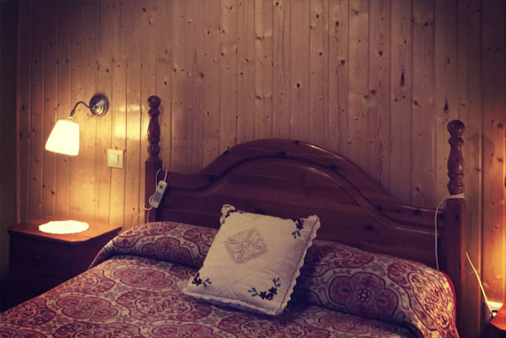 Detalle de cabecero. Esta fotografía pertenece a una reforma completa en donde se cambió por completo el aspecto de la misma. La estancia inicialmente presentaba techos excesivamente bajos, suelos muy fríos y una pésima distribución. Para reacondicionar esta estancia se elevó y aisló el techo (terminándolo con friso de abeto) eliminando desigualdades de los muros con paredes de pladur donde correspondía. También se trataron las vigas con anticarcoma, lijadas y tratadas con lasur. Se eliminó un armario empotrado que era el principal causante de la mala distribución. El suelo fue reacondicionado con tarima sintética flotante. También se presentó una nueva redistribución eléctrica haciendo más cómodo el uso de la habitación. El acabado de los muros fue realizado con pintura de teflón y un color que combinara con el friso de abeto. 